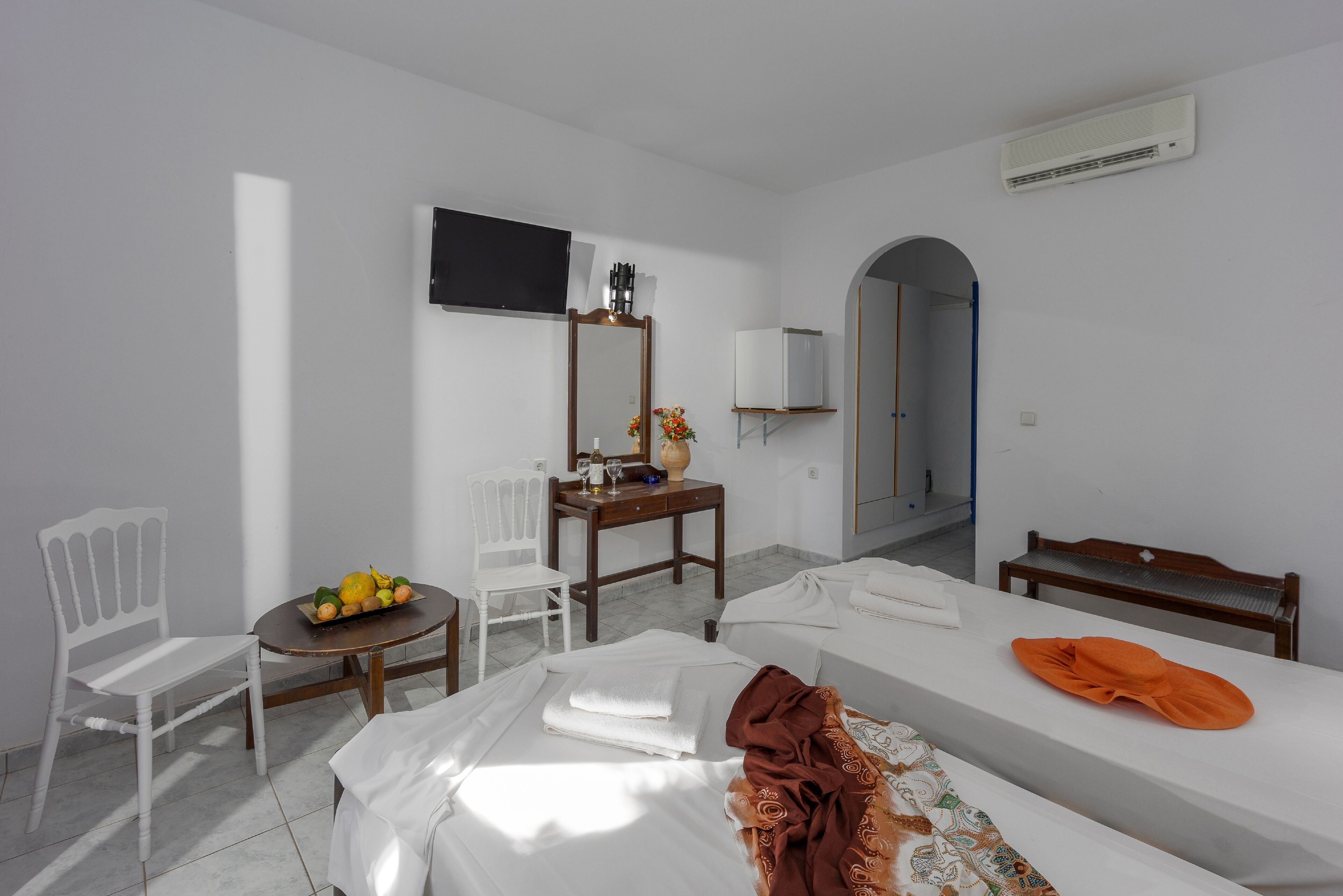 A hotel room with a bed, a desk, a chair, a TV, and a wardrobe.