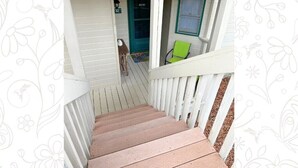 A wooden staircase leading to a porch with a green door, a window, and a green chair. - Apple Valley 32 at Rumbling Bald (Lake Lure)