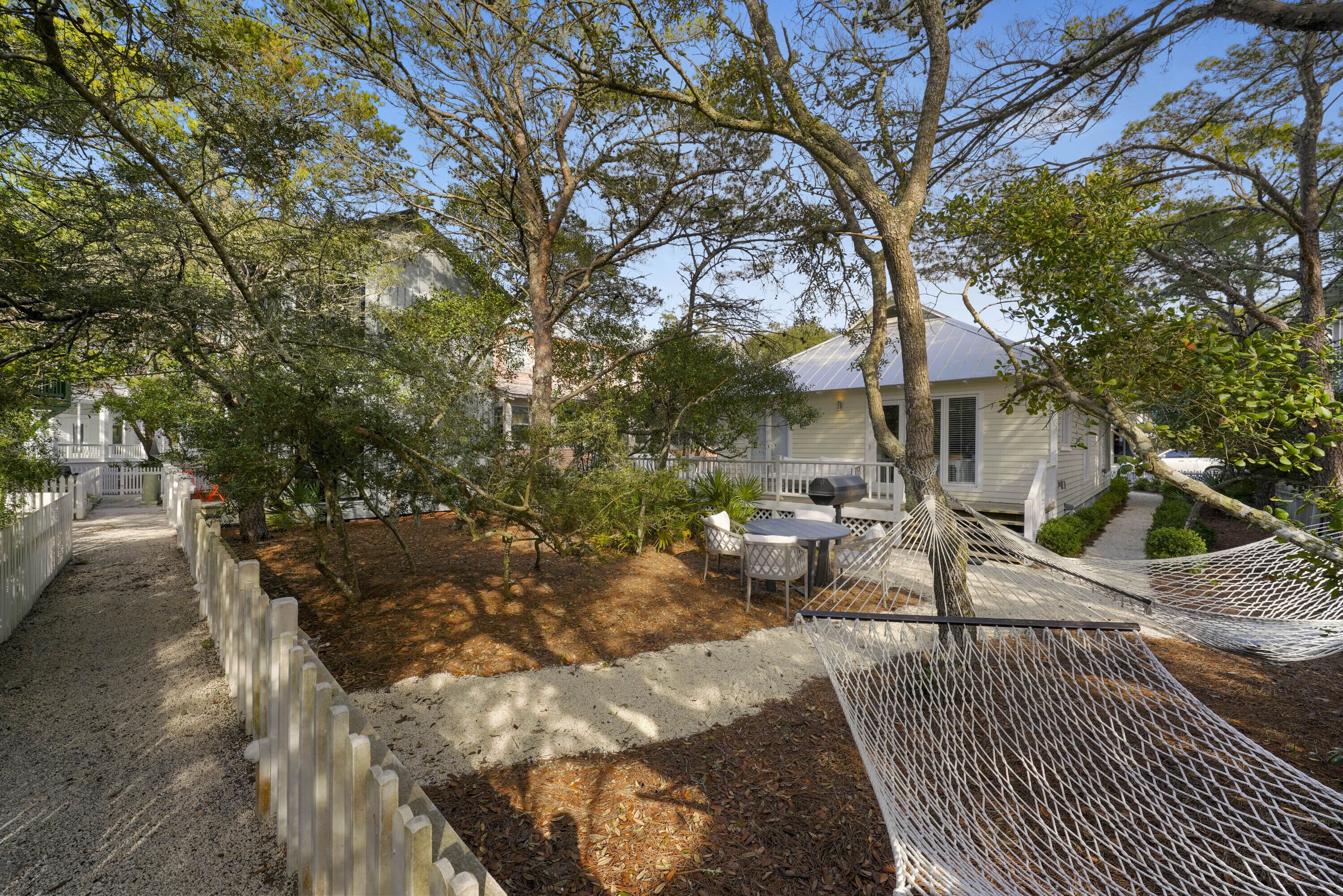 A fenced backyard with a hammock, a patio table, and chairs.