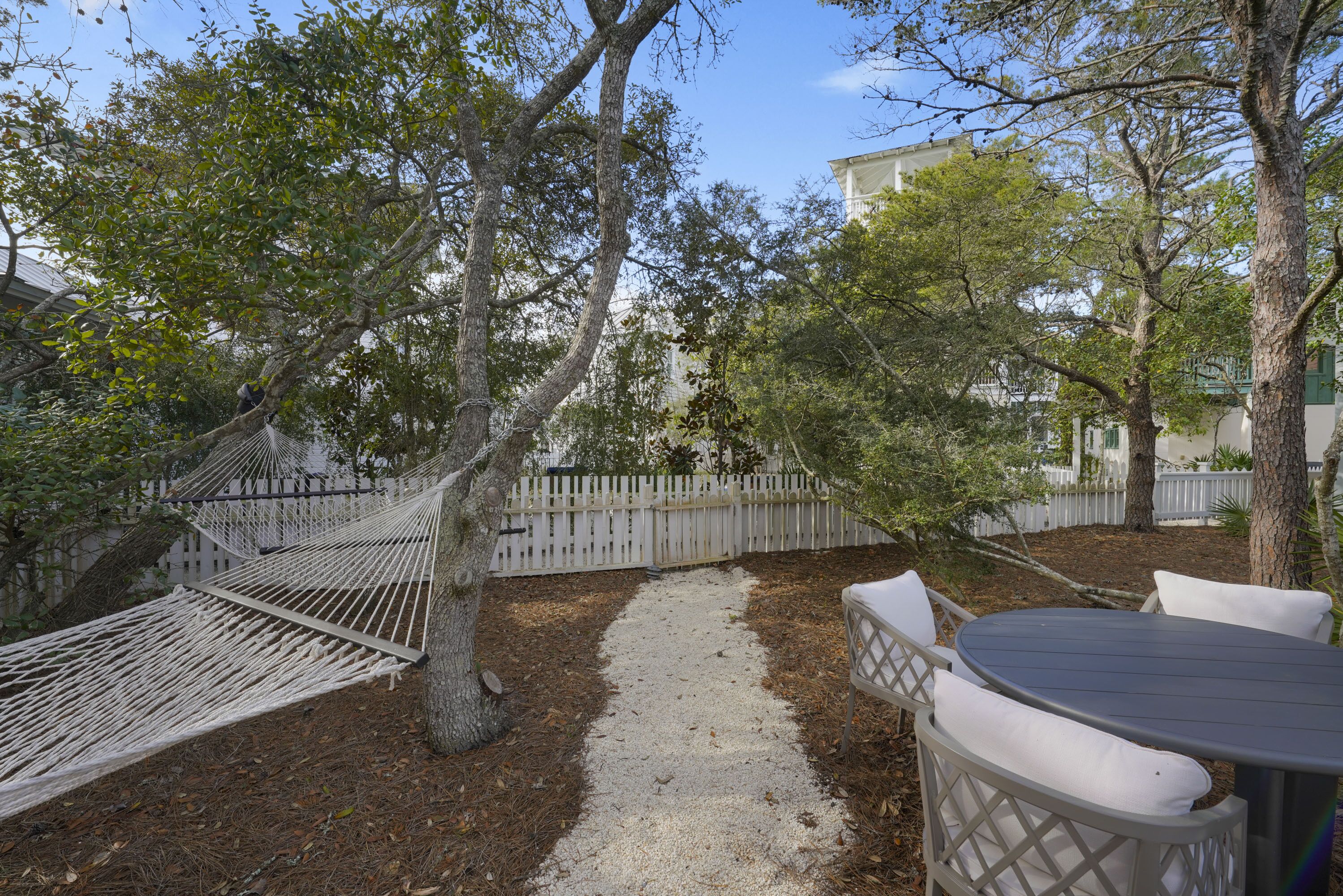 A hammock, a table with chairs, and a pathway in a backyard.