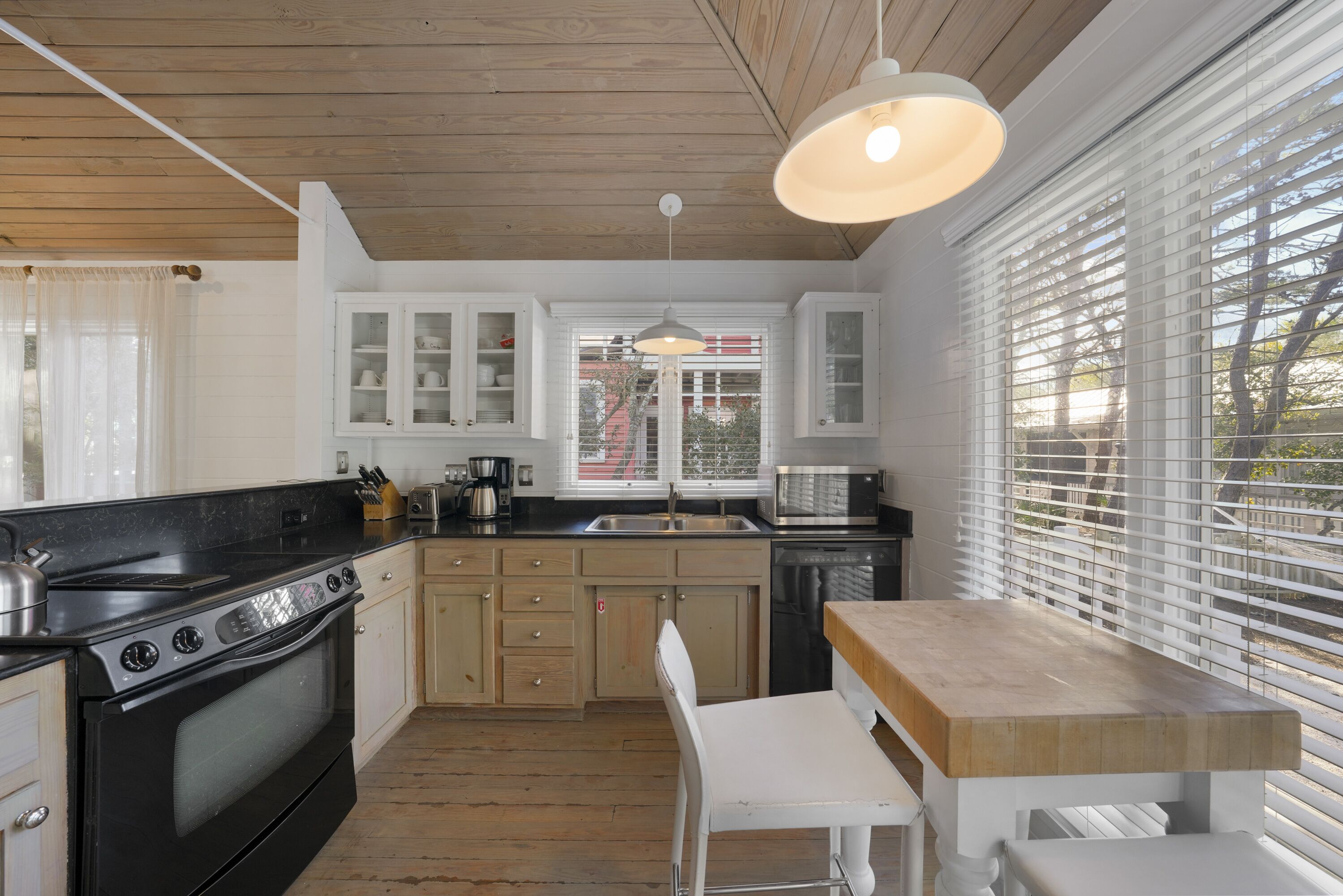 A kitchen with wooden cabinets, a stove, a sink, and a window with blinds.