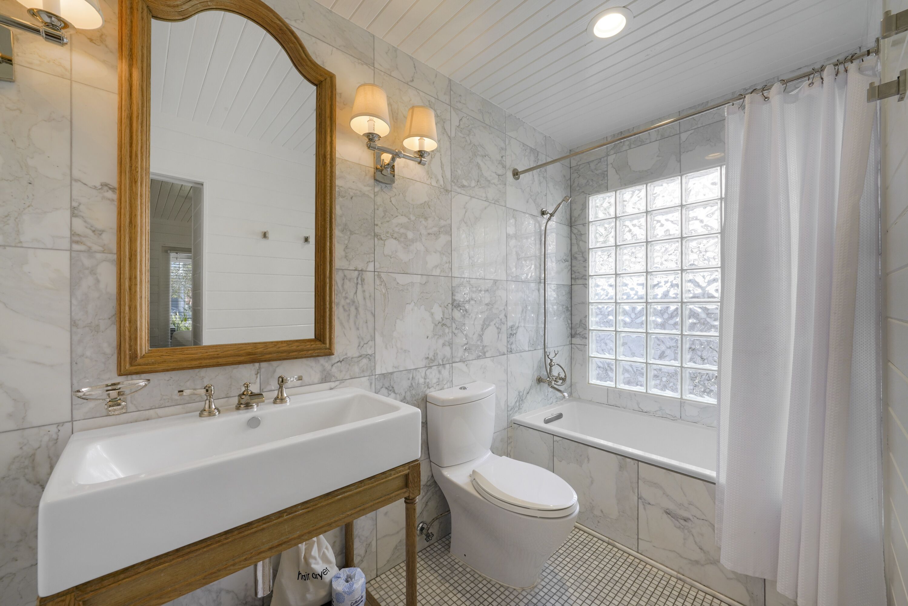 Un baño con lavamanos de mármol, inodoro, bañera y ventana con vistas.
