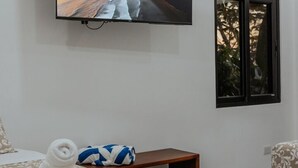 Una camera d'albergo con un letto, una TV a parete, una finestra e un tavolino.