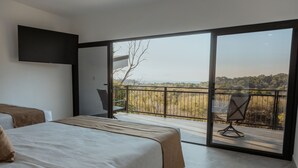 Una camera da letto con un letto grande, una TV a muro e un balcone con una sedia.