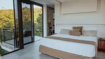 Un dormitorio moderno con una cama grande, un balcón con puertas de vidrio y vistas al verdor.