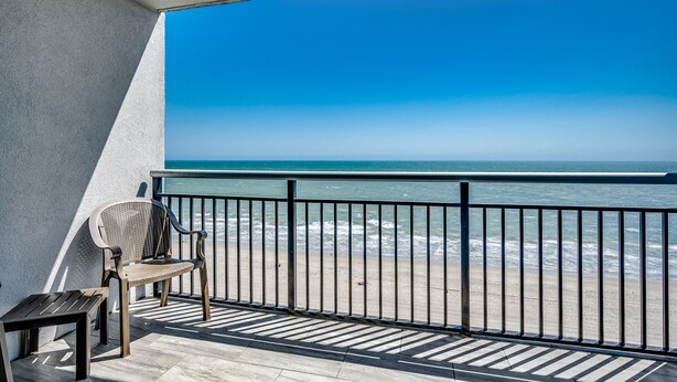 A balcony with a view of the ocean, a chair, and a small table. - 🌴Stunning Ocean Views | Pools + Hot Tub | Bay View Resort 1004A🌴 (Myrtle Beach)