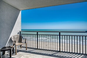 Un balcon avec vue sur l’océan, une chaise et une petite table.