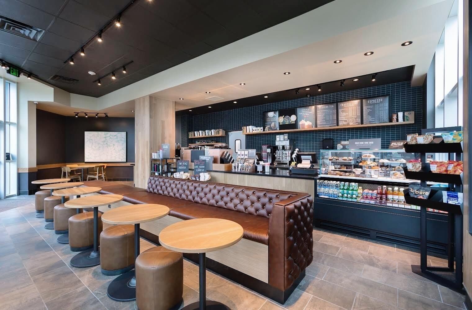A modern cafe with a bar area, seating, and a display of beverages and snacks.