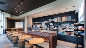 A modern cafe with a bar area, seating, and a display of beverages and snacks. - 🌴Stunning Ocean Views | Pools + Hot Tub | Bay View Resort 1005🌴 (Myrtle Beach)