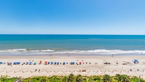 A beach with umbrellas and people, a clear sky, and the ocean. - 🌴Stunning Ocean Views | Pools + Hot Tub | Bay View Resort 1005🌴 (Myrtle Beach)