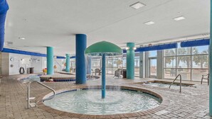 Uma área interna de piscina com um recurso central de água, vários espaços de estar e janelas amplas.