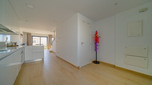 Une cuisine spacieuse équipée d’appareils modernes, un coin repas avec une table et des chaises, et une vue sur un balcon.