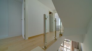 Un intérieur moderne avec un plancher en bois, des murs blancs et une balustrade en verre sur un escalier.