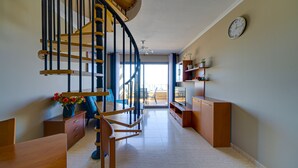A modern interior with a spiral staircase, wooden furniture, a clock on the wall, and a view to the outside.