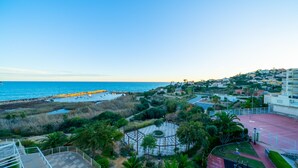 A coastal view with a beach, a tennis court, and residential buildings. - AL Piso de 2 dormitorios en El Campello (El Campello)