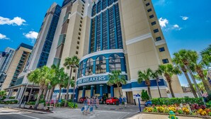 A hotel named "The Breakers" with a prominent curved entrance, tall buildings, and palm trees. - 💎Oceanfront~Lazy River~Awesome Amenities~Breakers Resort 1870💎 (Myrtle Beach)
