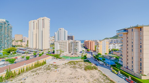 Eine Küstenstadt mit Hochhäusern, einem Strand und einer Straße mit Fahrzeugen.