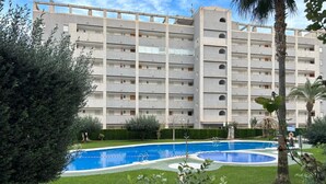 Ein mehrgeschossiges Gebäude mit einem Pool, umgeben von viel Grün.