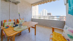 Ein Balkon mit einem Holztisch, Stühlen und Blick auf eine Stadtlandschaft.