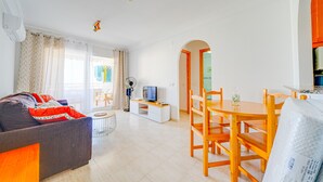 Ein modernes Wohnzimmer mit einer Couch, einem Fernseher und einem Essbereich.
