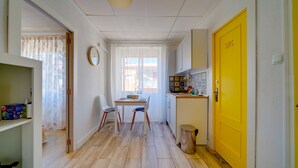 Una cocina compacta con zona de comedor, una puerta amarilla y un cesto de basura.