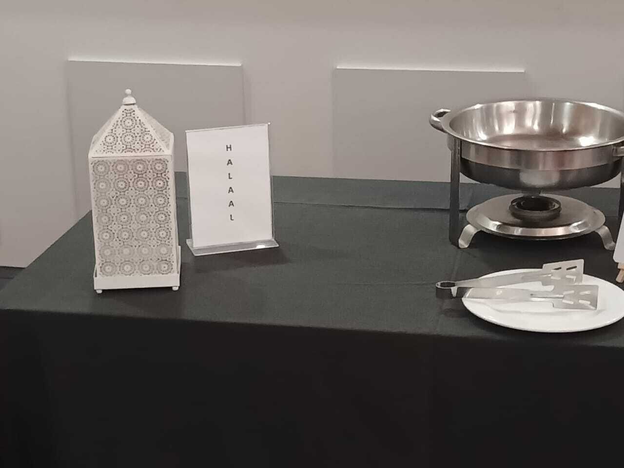 Ein Tisch mit einer Metallschüssel, einem weißen Teller und einer dekorativen Laterne.