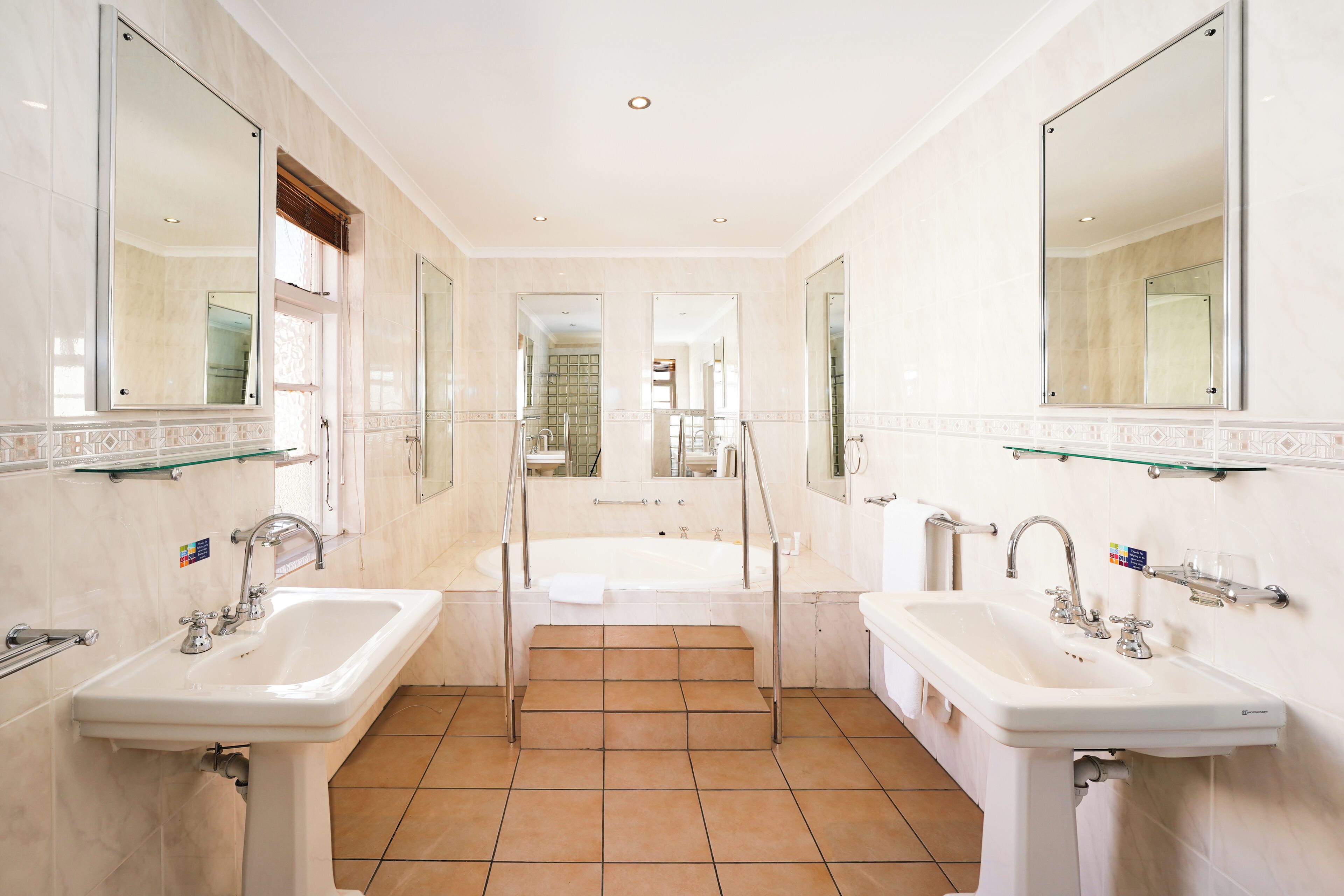 A spacious bathroom with two sinks, a bathtub, and a shower.