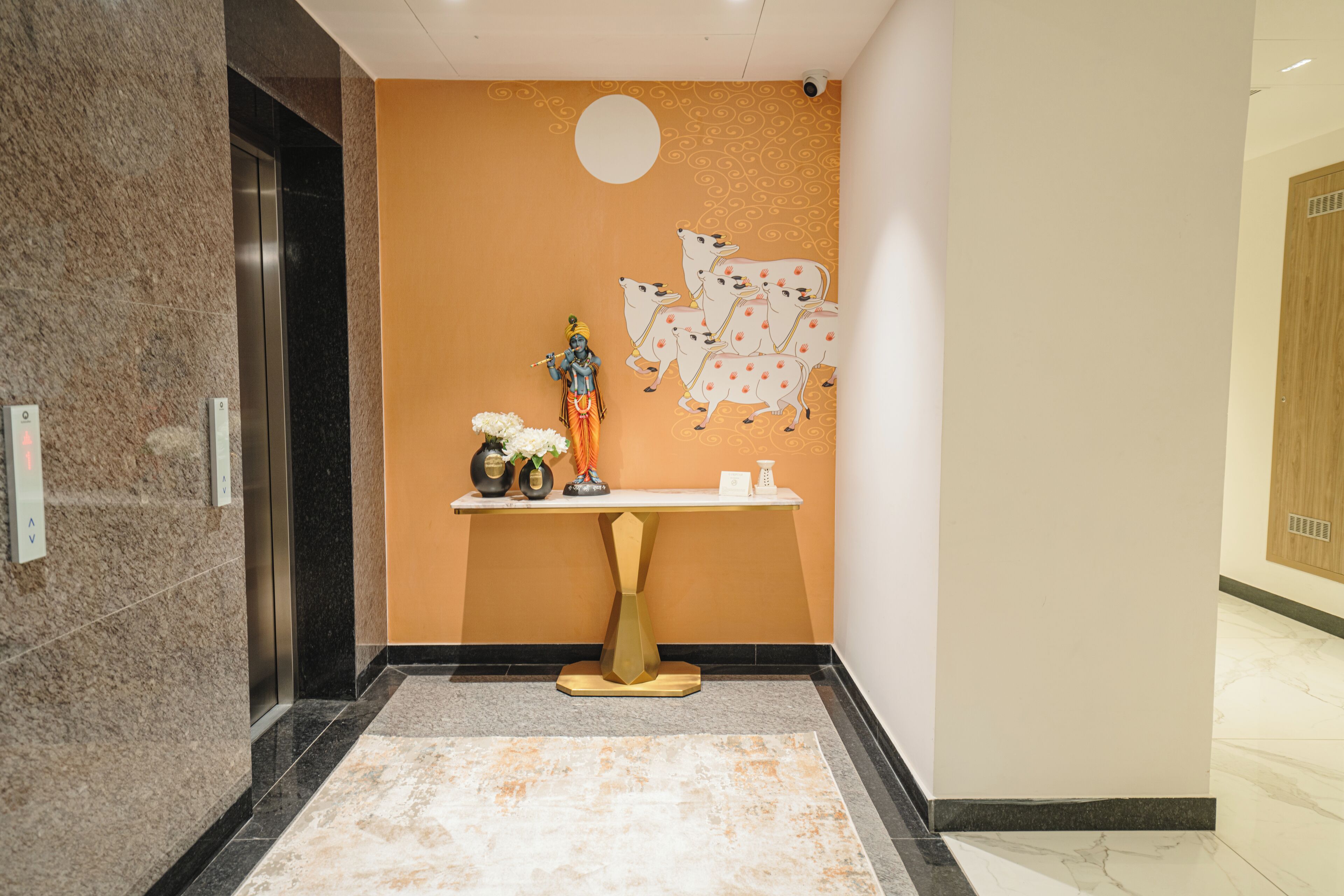 Un vestíbulo con piso de mármol, una estatua, un mural en la pared y una recepción.