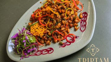 Une assiette de nourriture composée de pois chiches, de légumes et de diverses garnitures.