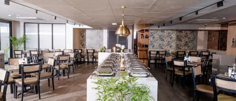 Un amplio comedor con mesas largas, sillas y una estación de buffet central.