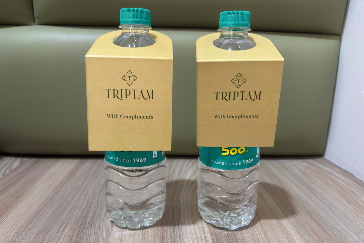 Dos botellas de agua TRIPTAM con cajas de cartón que indican 'TRIPTAM, con un obsequio' y '500 ml' sobre una superficie de madera.