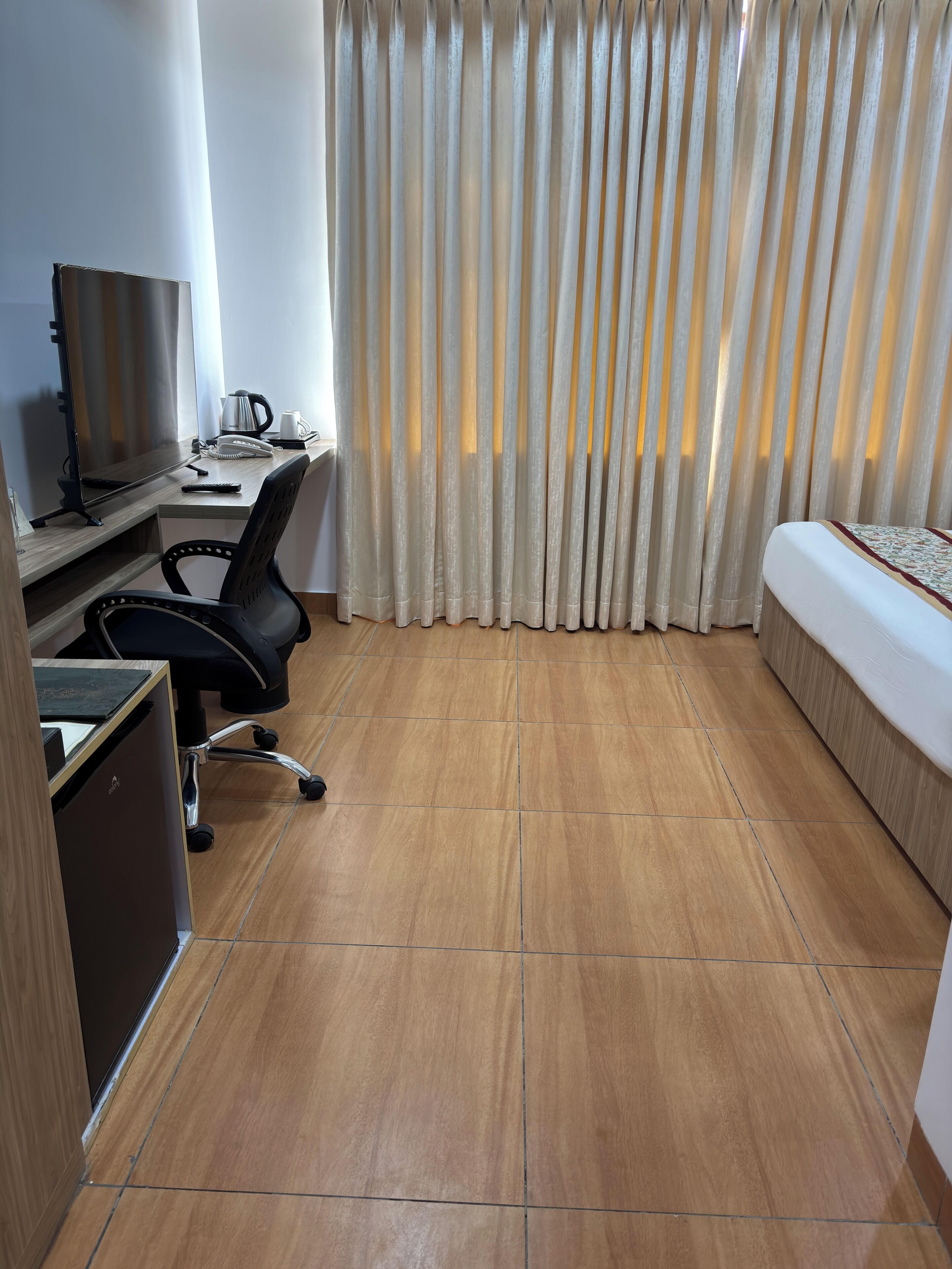 Una habitación de hotel con escritorio, silla, cama y cortinas.