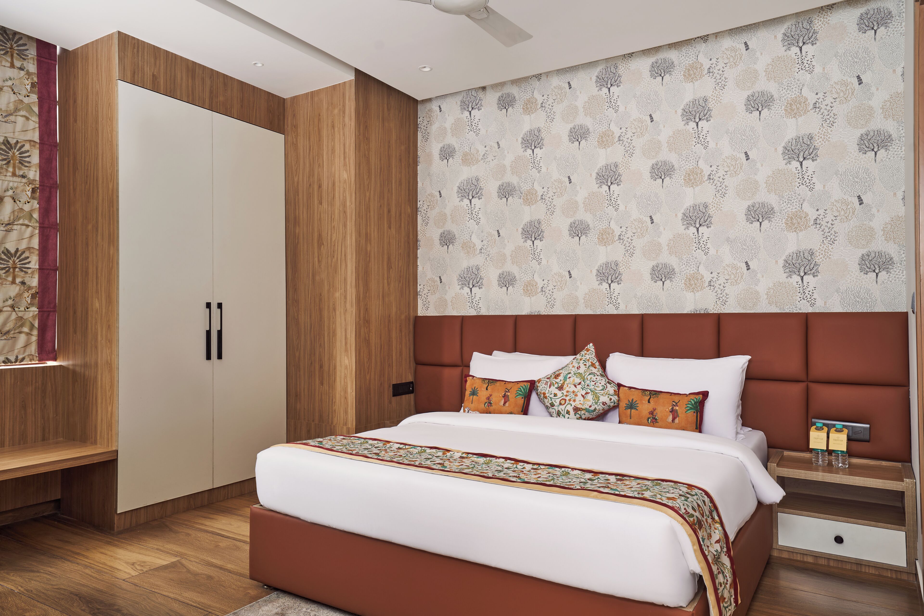 A modern bedroom with a large bed, wooden wardrobe, and a patterned wall.