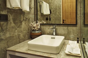 A bathroom with a marble countertop, a white sink, a vase with flowers, and a mirror above the sink.