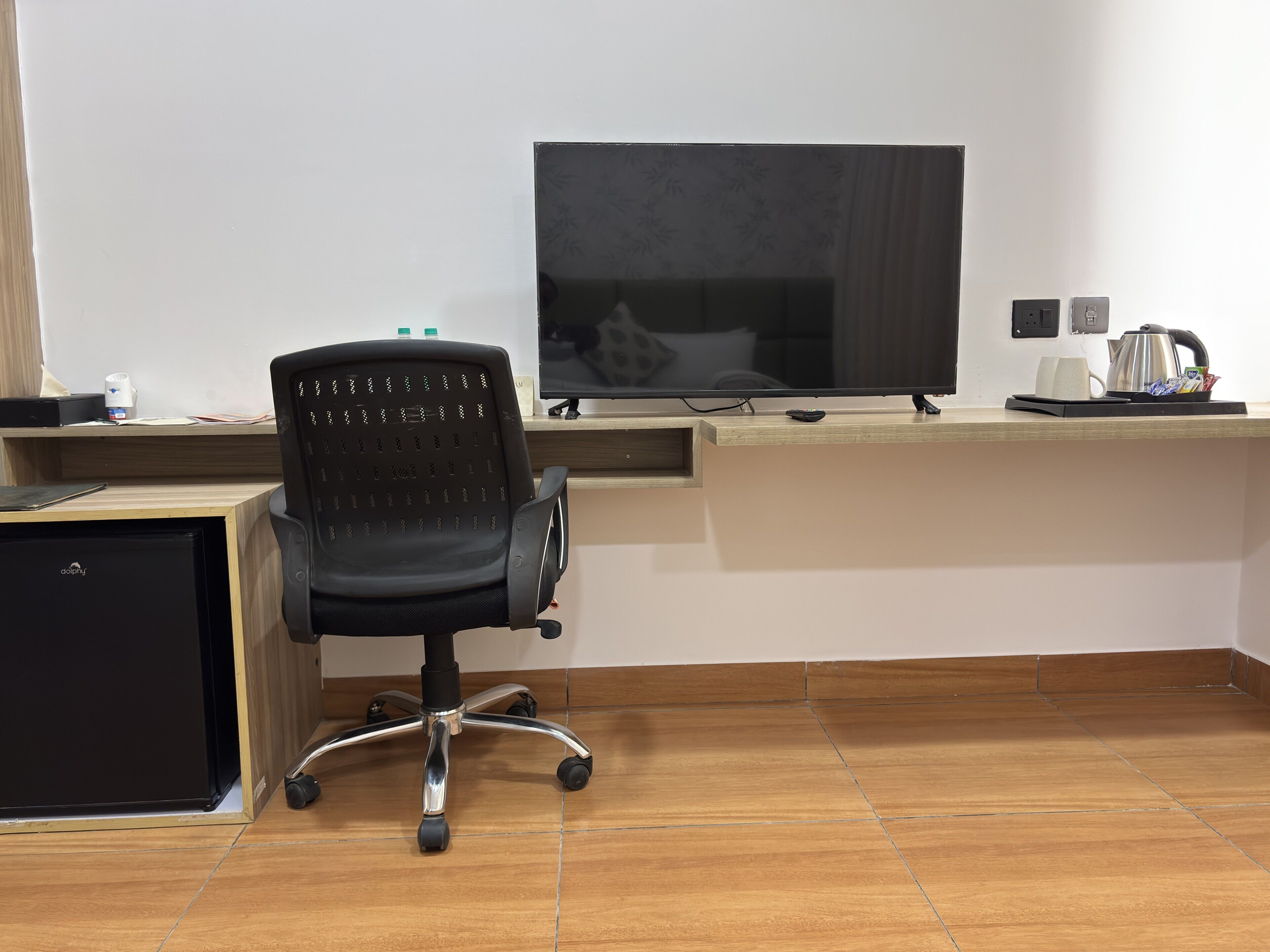 A modern office space with a desk, chair, computer monitor, and a coffee maker.