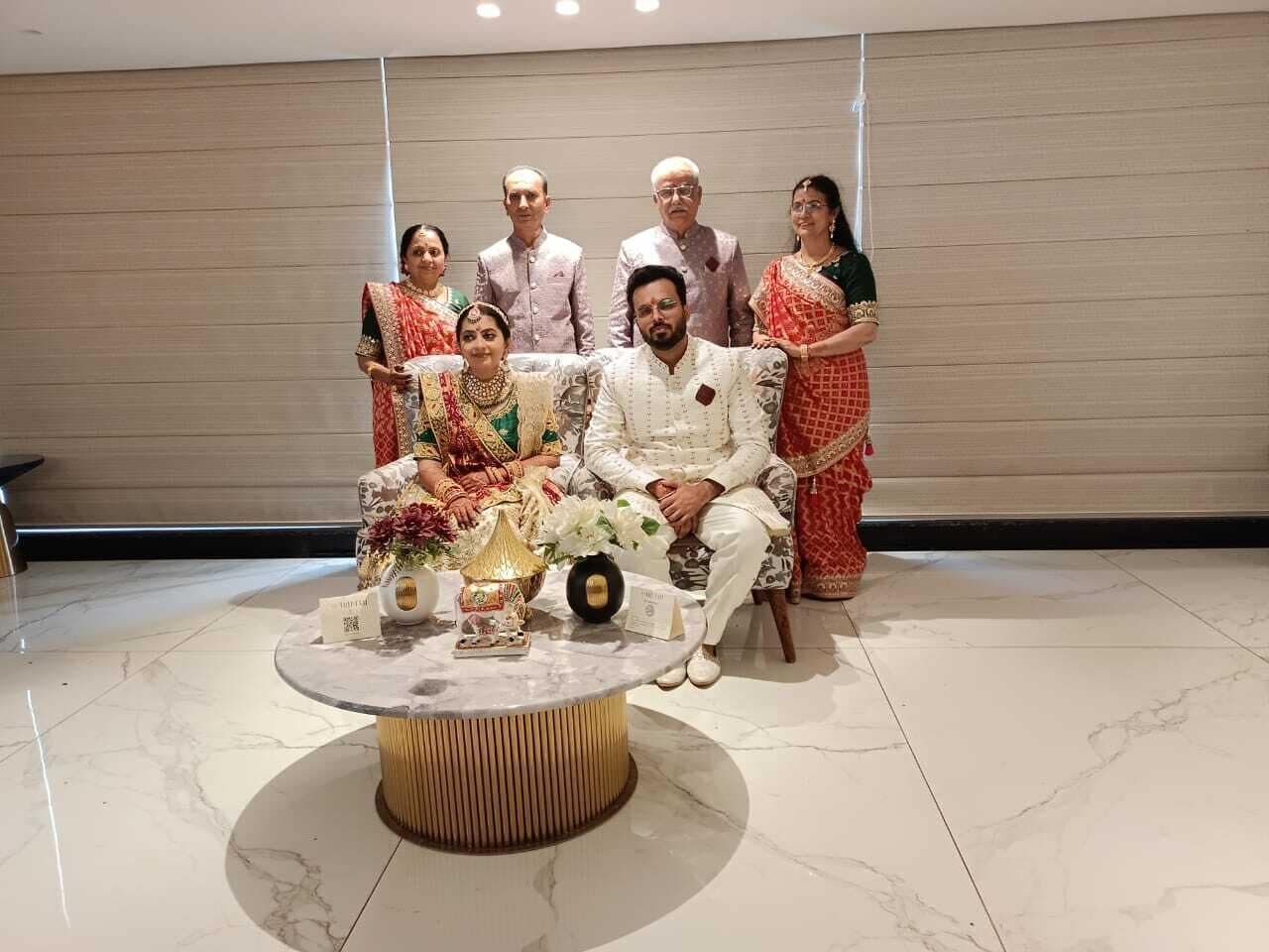 A group of people seated and standing in a room with a marble floor and a round table with a nameplate.