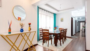 A modern dining area with a wooden table and chairs, a gold-framed console table, and decorative vases. - Lux suites Rosewood Park Apartments (Nairobi)
