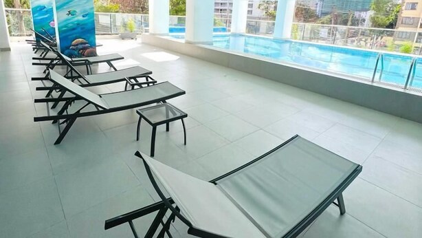 A spacious indoor area with a pool view, featuring multiple seating areas with tables and chairs. - Lux suites Rosewood Park Apartments (Nairobi)