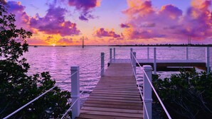 A wooden pier leading to a dock with a sunset view over water. - Sleep 16 guests over two side-by-side homes in exclusive Key Cove Landings (Key West)