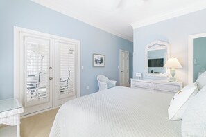 A bedroom with a large bed, a dresser, a chair, and a wardrobe with glass doors.