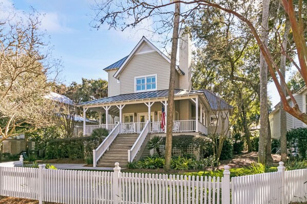 A two-story house with a porch, a staircase, and a white picket fence.