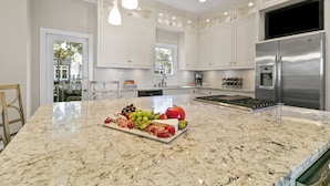 A modern kitchen with white cabinets, a stainless steel refrigerator, and a marble countertop with a fruit platter. - Popular location in Atlantic Beach, community pool (Kiawah Island)