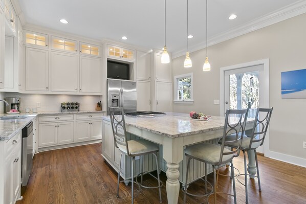 A spacious kitchen with white cabinetry, a large island with bar stools, stainless steel appliances, and pendant lighting. - Popular location in Atlantic Beach, community pool (Kiawah Island)