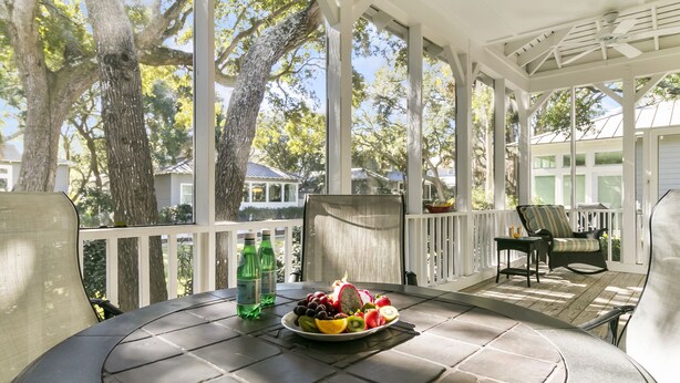 A covered patio with a round table, a plate of fruit, and two bottles of water. - Popular location in Atlantic Beach, community pool (Kiawah Island)