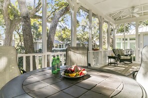 A covered patio with a round table, a plate of fruit, and two bottles of water. - Popular location in Atlantic Beach, community pool (Kiawah Island)