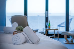 Relax in comfort with a large bed, a potted plant, and a side table featuring a bottle of water.