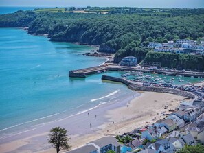 Une ville côtière dotée d’une plage de sable, d’un port de plaisance avec des bateaux et d’immeubles résidentiels.