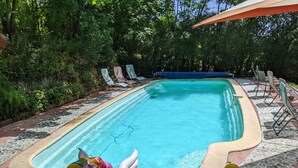 A swimming pool with inflatable unicorn floats, lounge chairs, and a covered area.