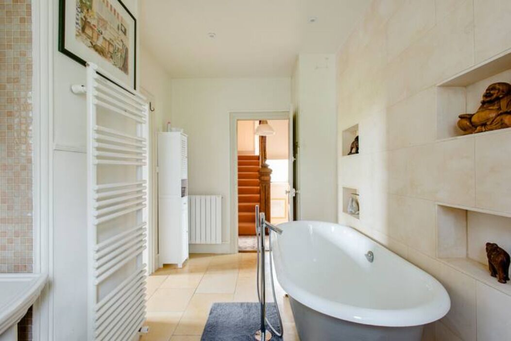A modern bathroom with a freestanding bathtub, a white radiator, and a tiled floor.