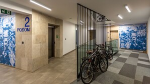 A hallway with a checkered floor, a number '2' sign, and bicycles parked near a glass railing.